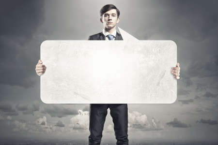 Young businessman showing blank white speech banner. Place for textの写真素材