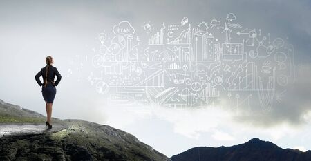 Back view of confident businesswoman with arms on waistの写真素材