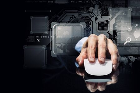 Hand of businessman in suit on dark digital background using wireless computer mouseの写真素材