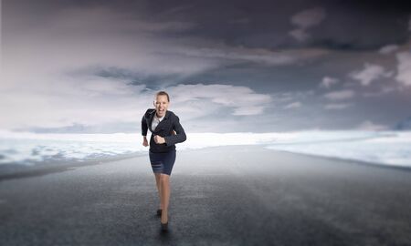 Young determined businesswoman competitor running on roadの写真素材