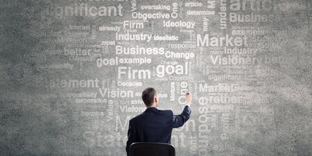 Rear view of businessman writing leadership conceptual words on wallの写真素材