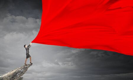 Young businesswoman in suit and bowler hat pulling curtainの写真素材