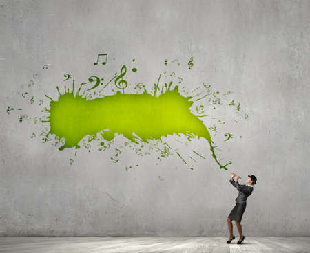 Cheerful businesswoman in suit and bowler hat playing fifeの写真素材