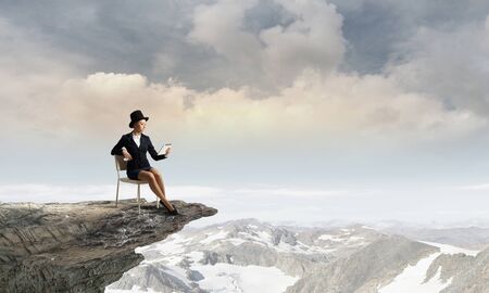 Pretty girl wearing retro hat siting on chair with tablet in handの写真素材