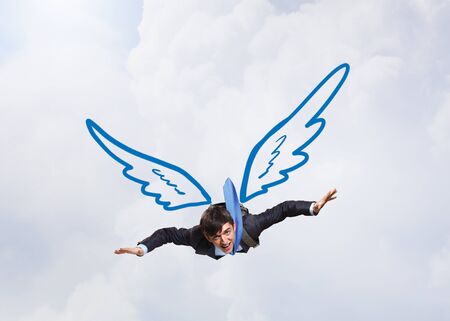 Young businessman with drawn wings flying in skyの写真素材