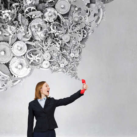 Portrait of young businesswoman with red phone receiver in hands
