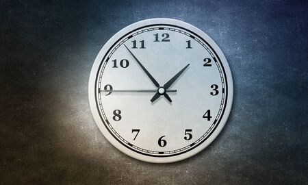Round wall clock hanging on grey concrete wall