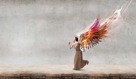 Attractive woman running with angel wings behind backの写真素材