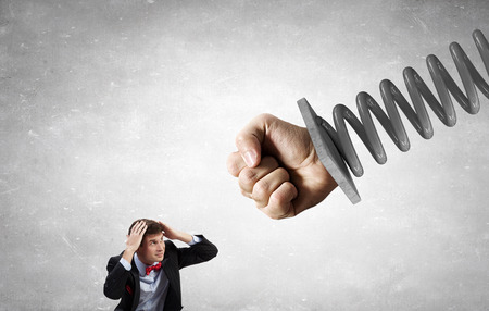 Young determined businessman fighting with human fist on springの写真素材