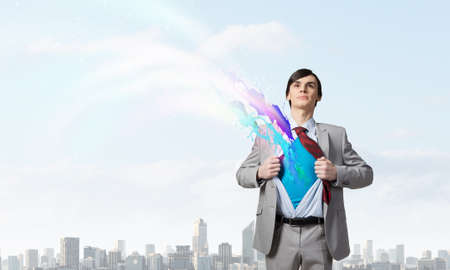 Young businessman acting like super hero and tearing his shirt offの写真素材