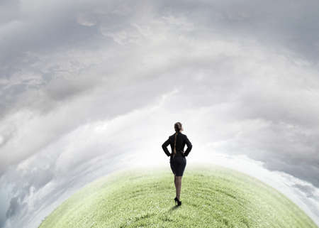 Back view of confident businesswoman with arms on waistの写真素材