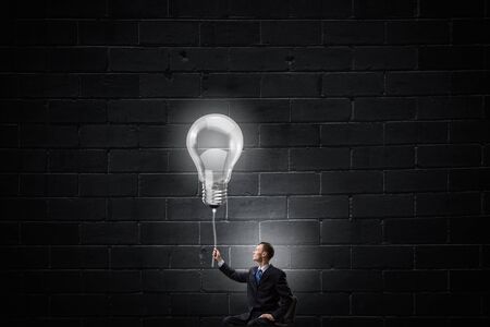 Businessman with bulb on rope representing bright ideaの写真素材