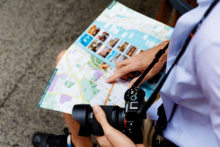 Happy male tourist in city with camera and mapの写真素材
