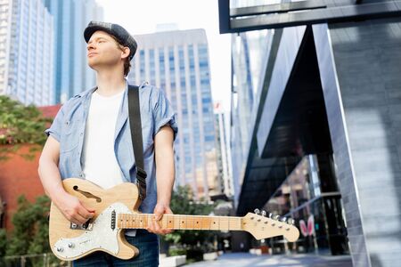Portrait of young musician with guitar in cityの写真素材
