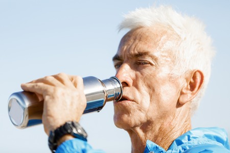 Handsome healthy man in sport wear drinking from sports bottleの写真素材