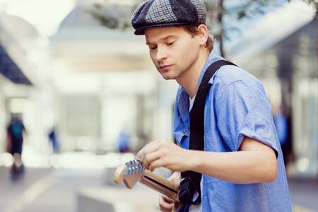 Portrait of young musician with guitar in cityの写真素材