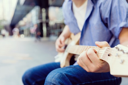 Portrait of young musician with guitar in cityの写真素材