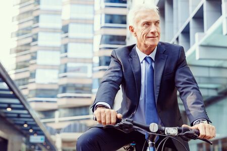 Successful businessman in suit riding bicycleの写真素材