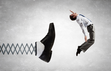 Businessman kicked by his boss foot on springの写真素材