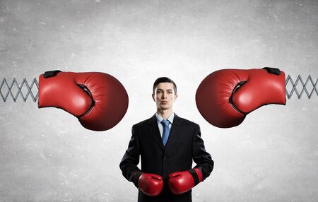 Determined businessman in boxing gloves fighting with glove on springの写真素材