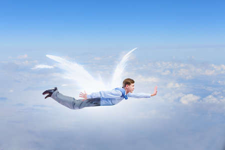 Young businessman with drawn wings flying in sky