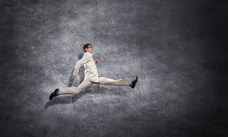Young businessman in jump over concrete backgroundの写真素材