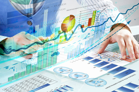 Close up of business person investigating infographs with magnifier Close up of business person investigating infographs with magnifier