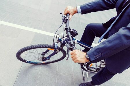 Successful businessman in suit riding bicycleの写真素材