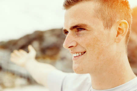 Young man in sport wear with outstretched arms standing on beach
