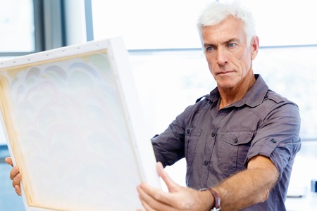 Man standing in a gallery and contemplating abstract artworkの写真素材