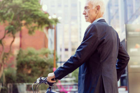 Successful businessman in suit riding bicycleの写真素材