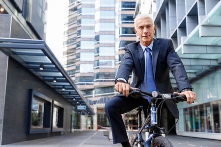 Successful businessman in suit riding bicycleの写真素材