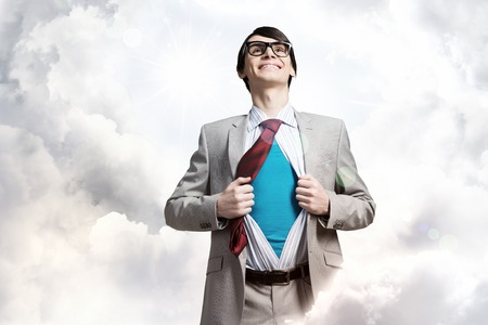 Young smiling businessman acting like super hero and tearing his shirt offの写真素材