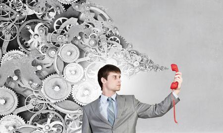 Determined businessman talking on red phone handsetの写真素材