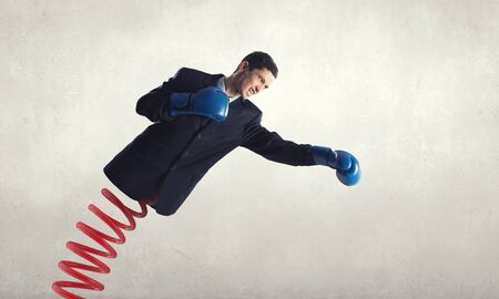 Determined businessman in boxing gloves on spring