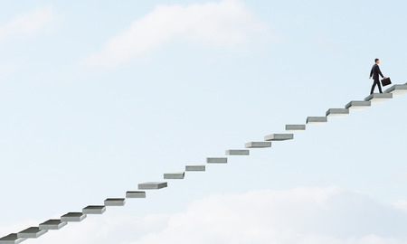 Young businessman walking up on staircase representing success conceptの写真素材
