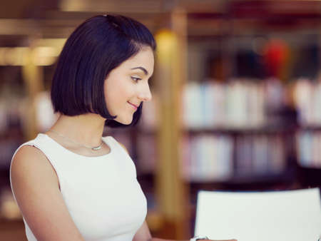 Happy young female student sudying at the libraryの写真素材