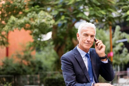 Portrait of confident businessman with his mobile phone outdoorsの写真素材