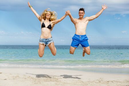 Travel concept of young couple cheering for summer holidays on beachの写真素材