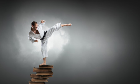 Young determined karate man on pile of booksの写真素材