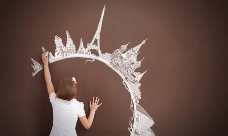 Cute little girl standing with back and drawing travel concept on blackboardの写真素材