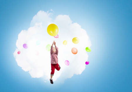 Little happy cute boy flying on balloonの写真素材