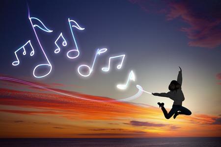 Young girl jumping high in sky and drawing music conceptの写真素材