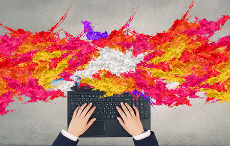 Top view of businesswoman hands using laptop and colorful splashes on screenの写真素材