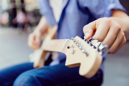 Hands of musician tuning his guitar outsideの写真素材