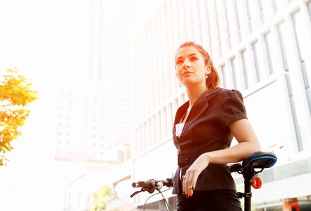 Young woman in business wear commuting on bicycle in cityの写真素材