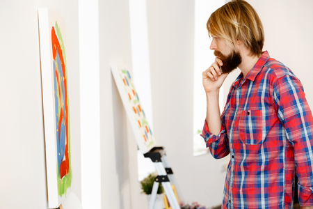 Man standing in a gallery and contemplating abstract artworkの写真素材