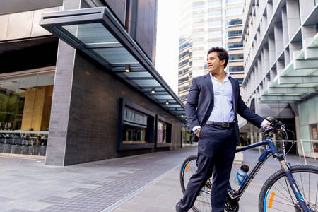 Successful businessman in suit riding bicycleの写真素材