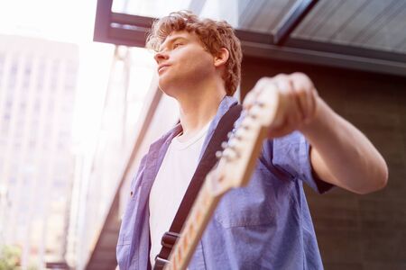 Portrait of young musician with guitar in cityの写真素材