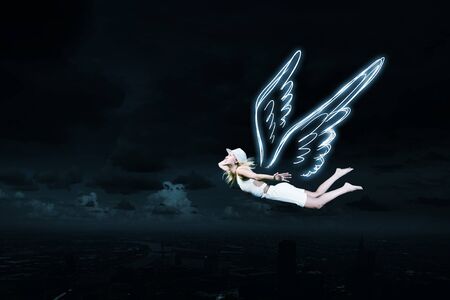 Cute girl with angel drawn wings on dark sky backgroundの写真素材